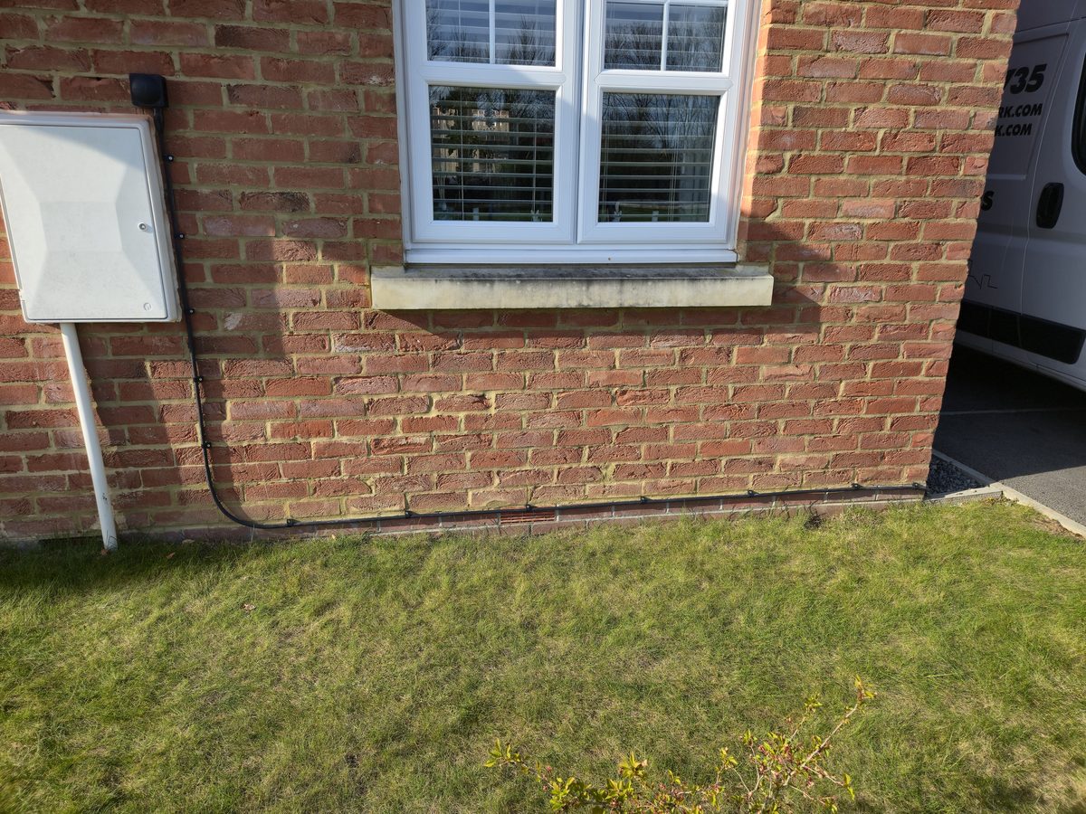 SWA cable routed neatly along the external brick wall from house to garage