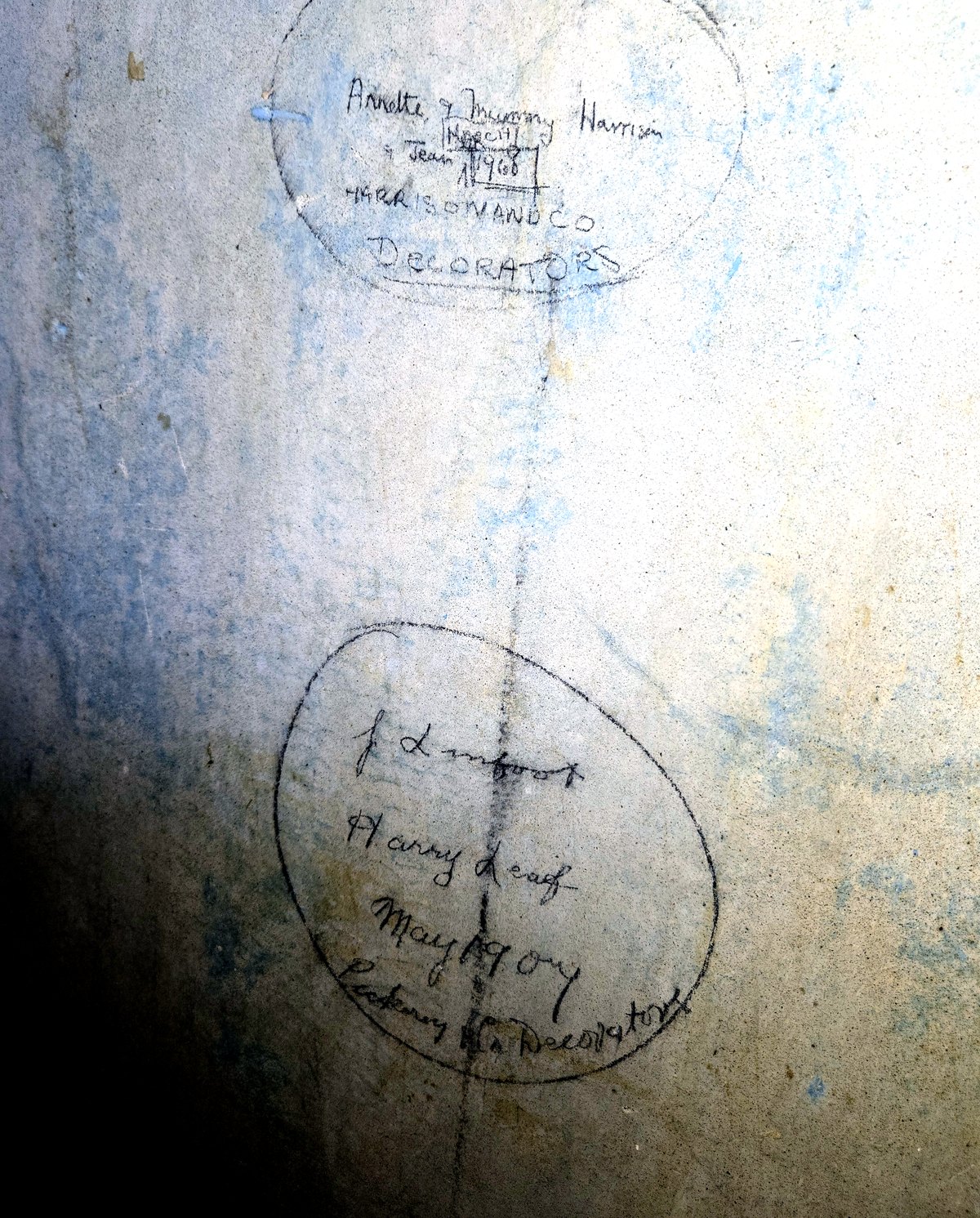 Two pencil circles on a stripped plaster wall, each containing handwritten names