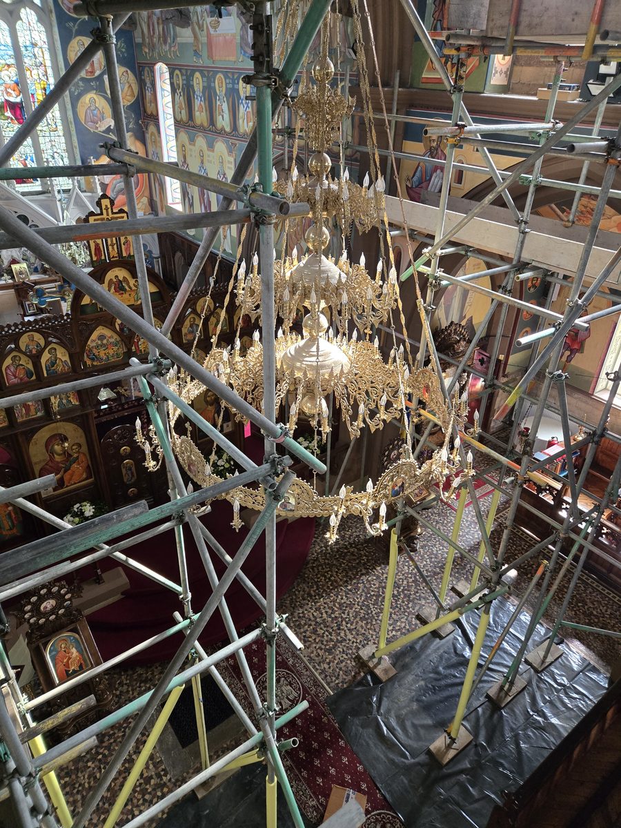 Ornate church chandelier surrounded by scaffolding during lighting renovation